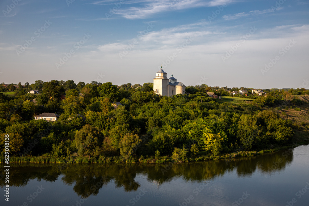 Fototapeta premium The old church above the river in the Ukrainian village on a summer evening.