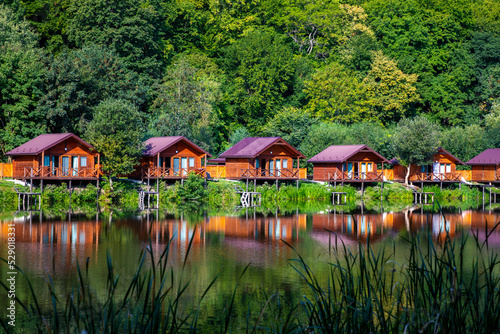 Wooden houses on the water near the forest for carp fishing. A place to relax in nature. Autumn carp fishing season. photo