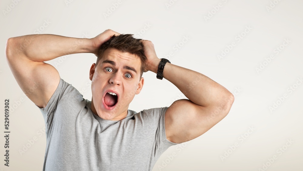 Excited shocked man holding hands on face and screaming looking at camera with big eyes and open mouth, shocked bemused with news, win at lottery on background Excited shocked man holding hands on face and screaming looking at camera with big eyes and open mouth, shocked bemused with news, win at lottery on background