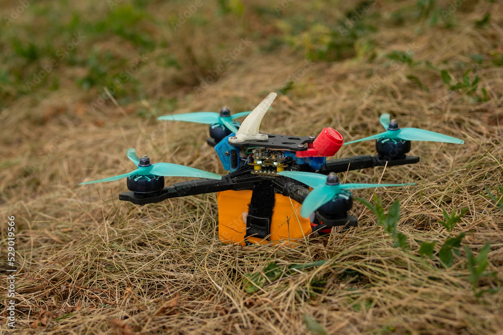 Naklejka premium Sports FPV drone takes off quickly from grass in field.