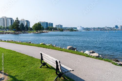 Centennial Park walking Path and wooden bench. Downtown Barrie curves around the shore of Kempenfelt Bay, Lake Simcoe in summer time. Ontario, Canada. photo