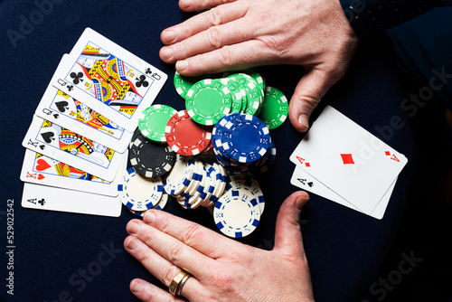 Unrecognizable man going All-In in a game of poker. He holds two aces.