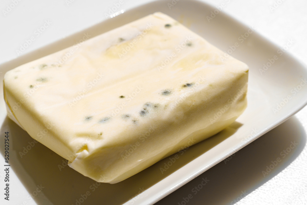 a pack of spoiled butter with mold on a white background. 