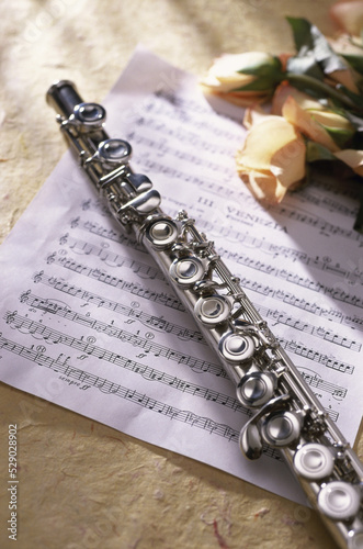 Close-up of a flute on music sheets near roses photo