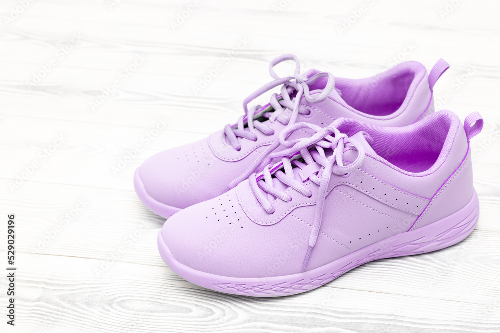 Pink purple sneakers stand on a white wooden background. Shoes with laces top view, flat lay. The concept of sport, running and outdoor activities. Take off your shoes at home.