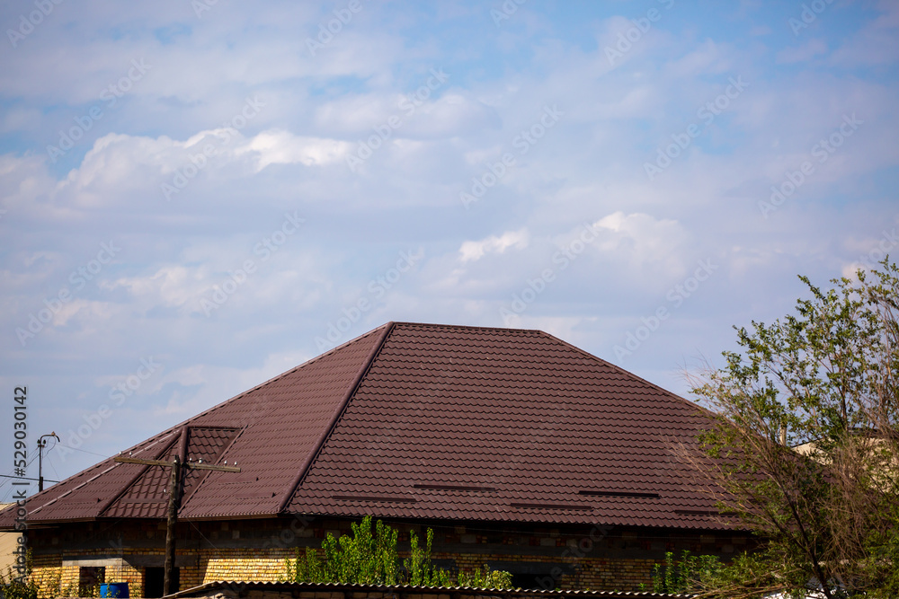 Roofs of houses from a metal profile against the sky. Roofing. Metal tiles on the roofs of houses. Roofs of houses from a metal profile against the sky. Roofing. Metal tiles on the roofs of houses.