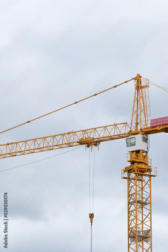 Yellow building constraction tower crane against gray sky