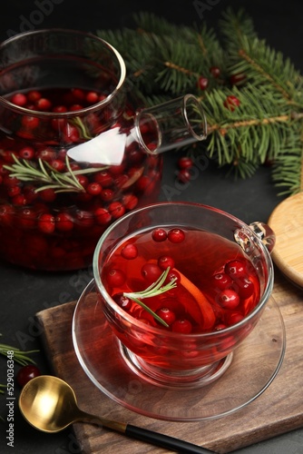 Tasty hot cranberry tea with rosemary and lemon on black table