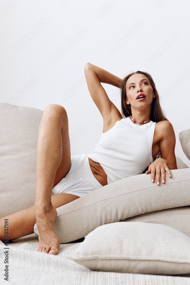 Beautiful woman model poses lying on pillows on the floor with tanned skin caring for her body, beauty treatments at home, a beautiful healthy body Beautiful woman model poses lying on pillows on the floor with tanned skin caring for her body, beauty treatments at home, a beautiful healthy body