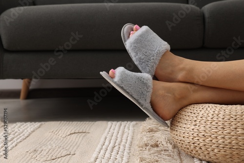 Woman wearing grey soft slippers in room, closeup. Space for text photo