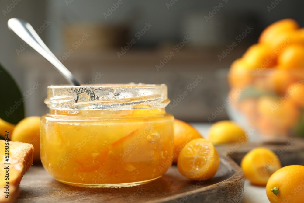 Delicious kumquat jam in jar and fresh fruits on wooden board, closeup. Space for text Delicious kumquat jam in jar and fresh fruits on wooden board, closeup. Space for text