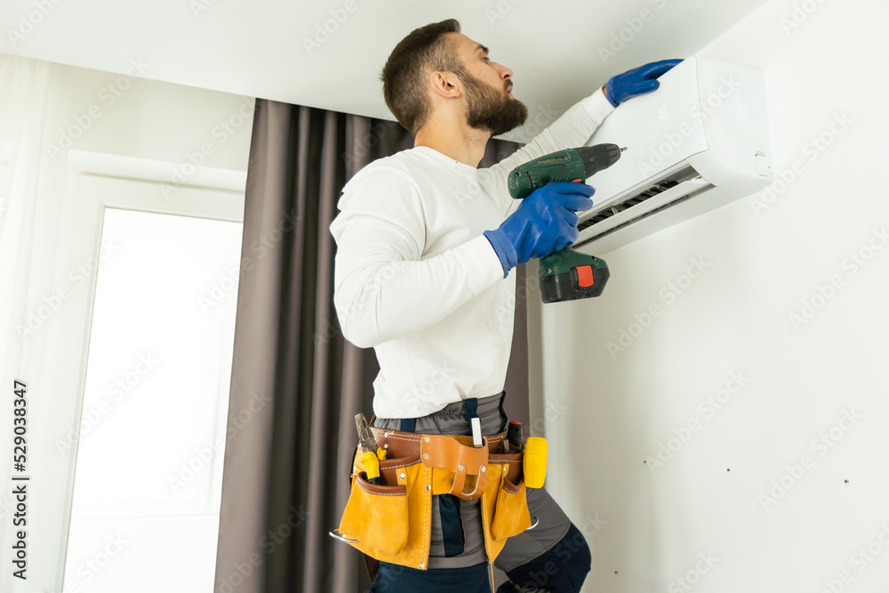 Male technician fixing air conditioner indoors. Male technician fixing air conditioner indoors.