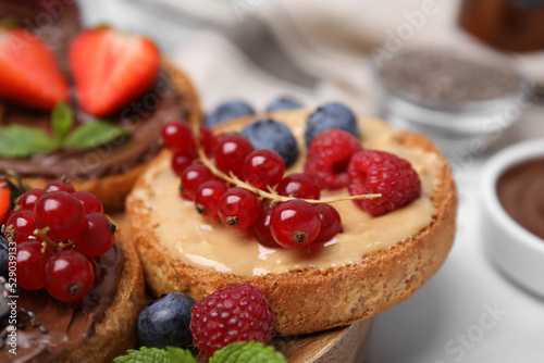 Tasty organic rusks with different toppings and ingredients on white table, closeup