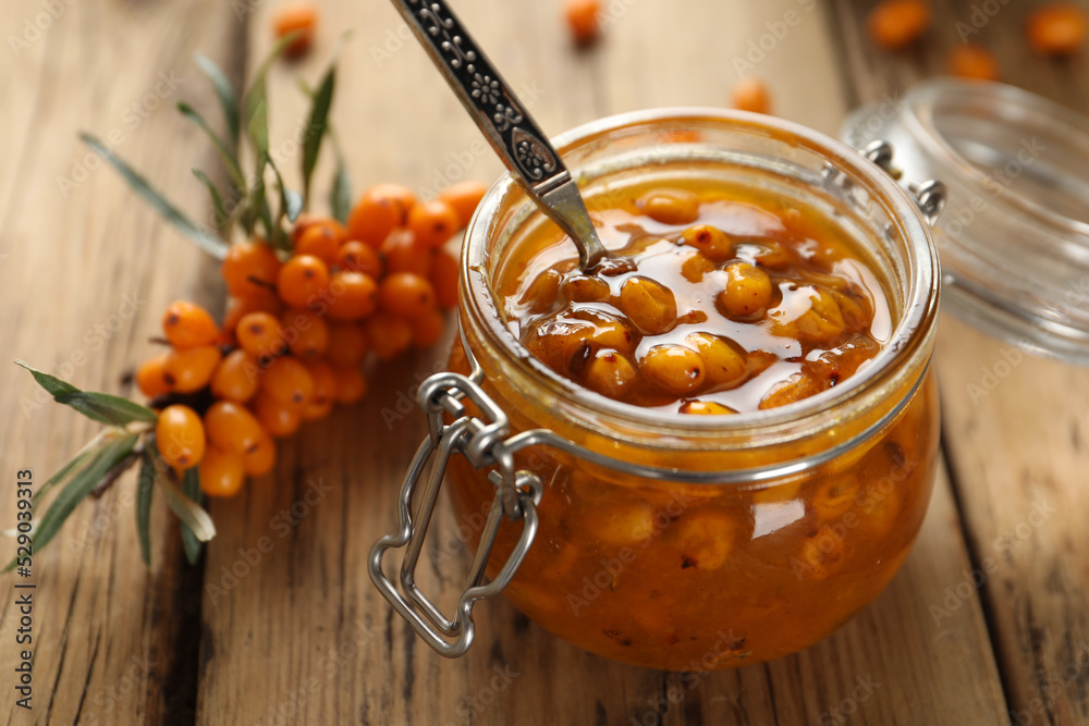 Delicious sea buckthorn jam and fresh berries on wooden table, closeup Delicious sea buckthorn jam and fresh berries on wooden table, closeup