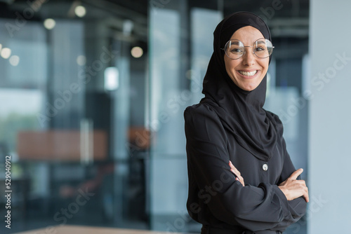 Carta da parati Portrait of muslim woman in hijab at work in office, business woman smiling and looking at camera with crossed arms