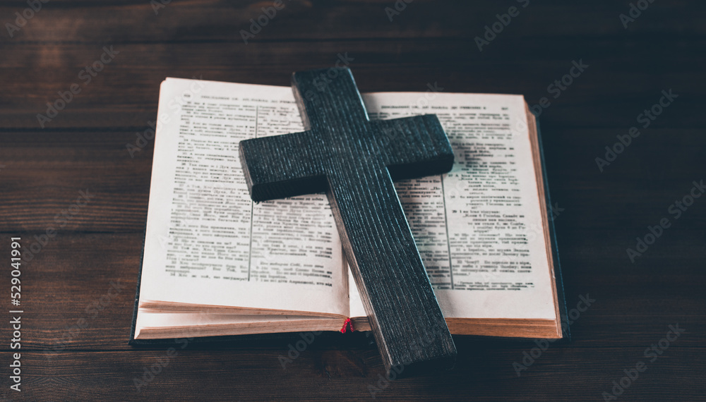 Open Bible. Cross crucifixion. The concept of God's love. On a wooden background.