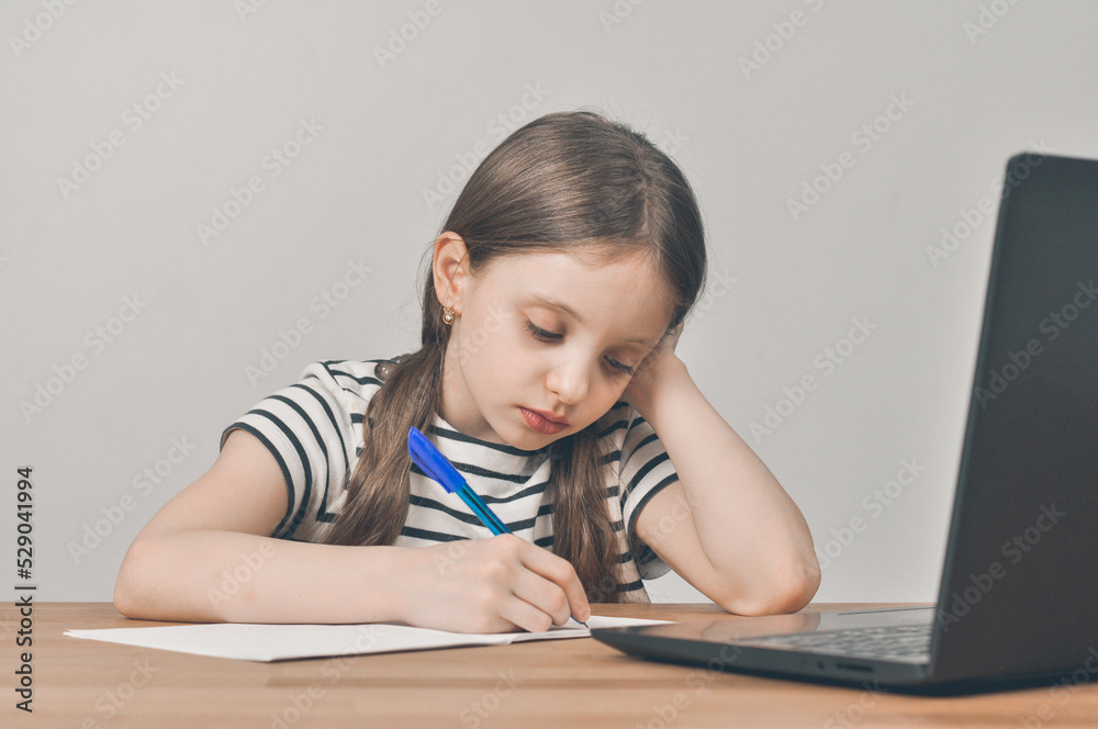 European girl with a laptop. Sitting at the table doing homework. Online learning European girl with a laptop. Sitting at the table doing homework. Online learning