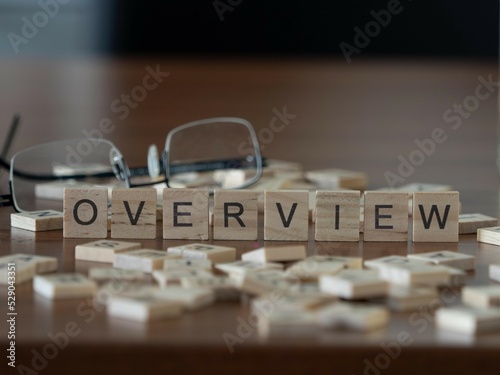 overview word or concept represented by wooden letter tiles on a wooden table with glasses and a book