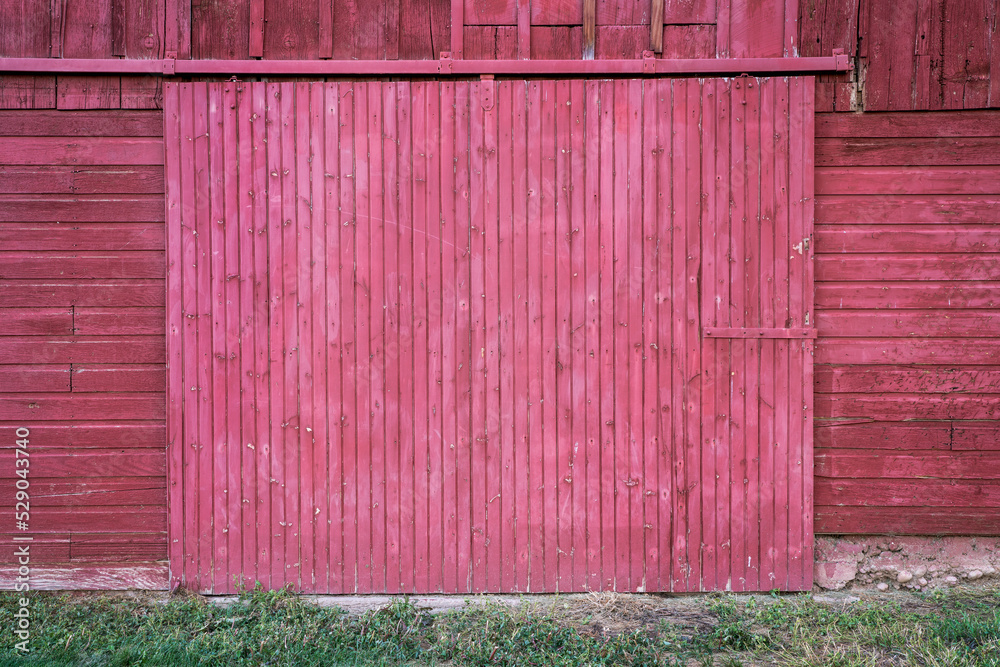 wall of old, wooden, weathered red painted barn with a sliding gate - rustic wood background and texture wall of old, wooden, weathered red painted barn with a sliding gate - rustic wood background and texture