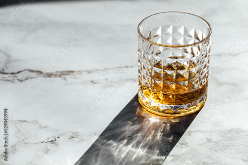 Fotografie, Obraz photography of scotch whisky glass in a marble table with light and shadow