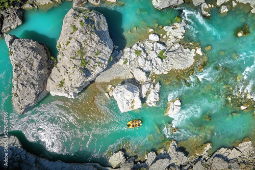 White water rafting.  Adventure and sport. A yellow raft floating among the rocks on the crystal clear, blue-green water. Perpendicular drone view of the rafters floating on Vjose river, Albania.  photo