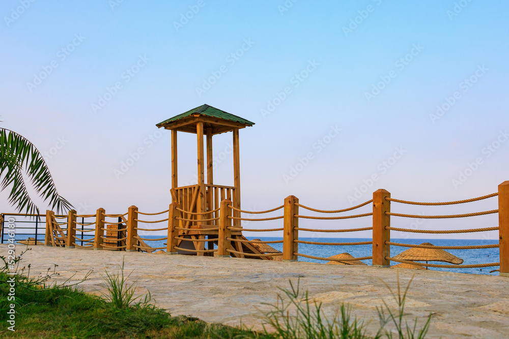 A wooden watchtower on the embankment for lifeguards to watch swimming tourists having a rest. Background