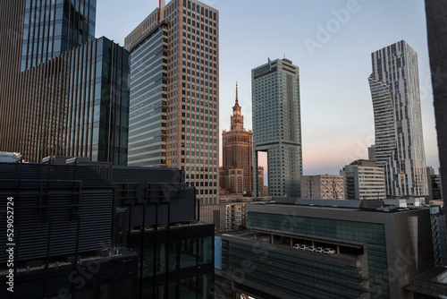 Fototapeta Naklejka Na Ścianę i Meble -  Amazing modern European city of Warsaw, Poland with its tall office buildings and the historic Palace of Culture. Urban backdrop with buildings. Downtown at evening
