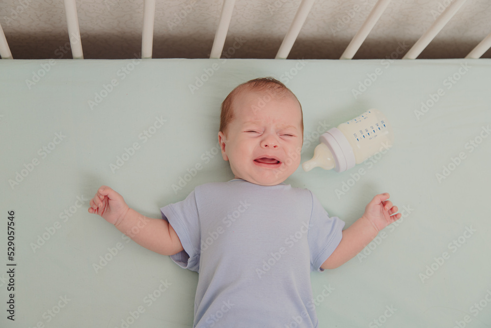 A hungry baby is crying in the crib . Baby crying. Children 's emotions