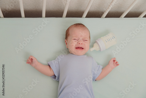 A hungry baby is crying in the crib . Baby crying. Children 's emotions . Pain during teething. A hungry child. Children's colic in the stomach.