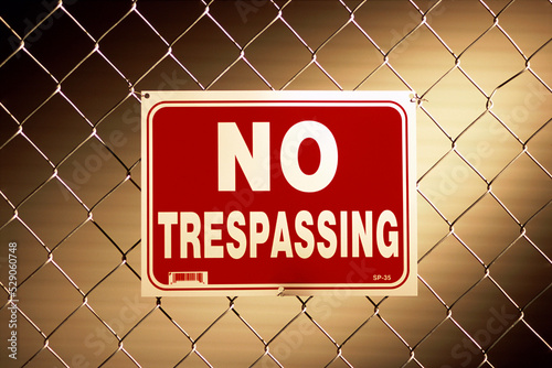 No trespassing sign on a chain-link fence photo