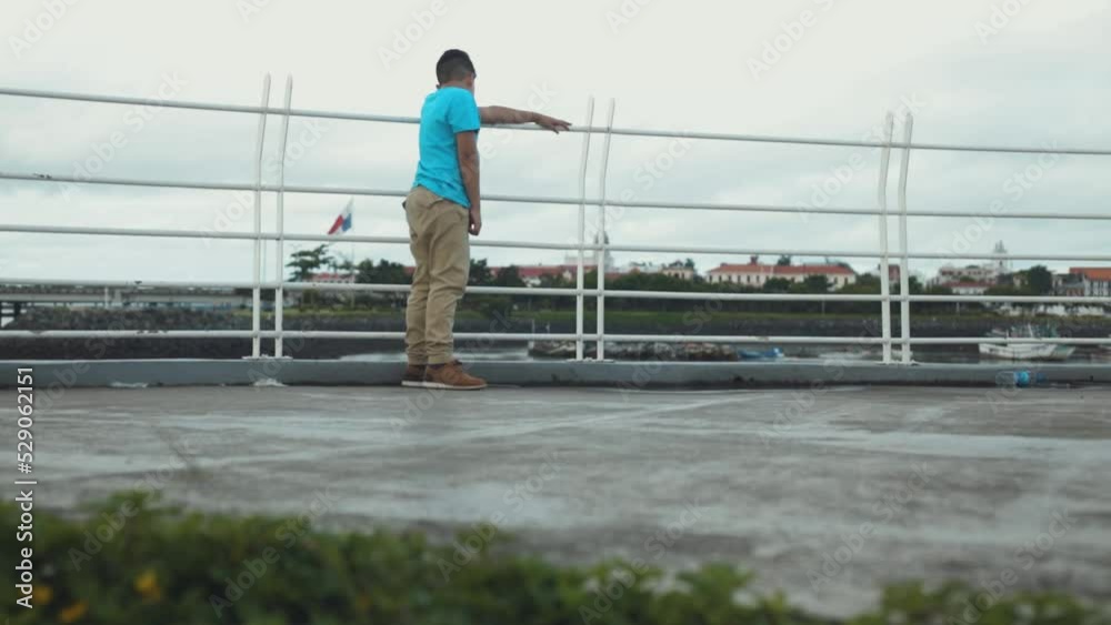 latin boy looking at the sea leaning against the railing, medium shot latin boy looking at the sea leaning against the railing, medium shot