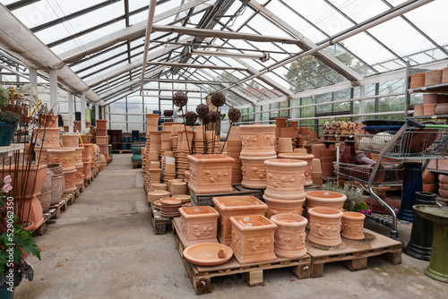 Various ceramic terra cotta pots in a DIY store. Small and large ceramic pots in glass house.