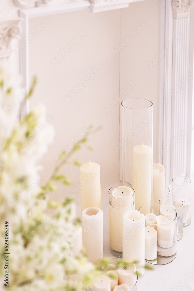 Classic fireplace in wedding decor. Candles in glass vases surrounded by white flowers. Selective focus. Classic fireplace in wedding decor. Candles in glass vases surrounded by white flowers. Selective focus.