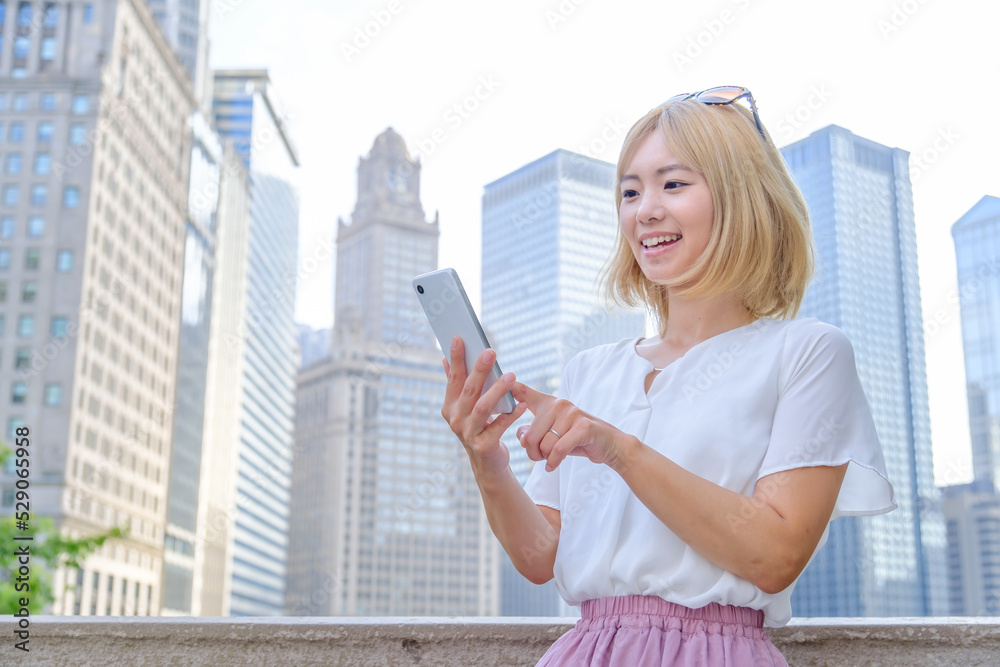 海外旅行でスマートフォンを使う金髪の女性