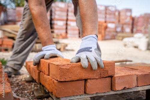 man construction industry or warehouse worker stacking clay brick