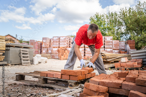 man construction industry or warehouse worker stacking clay brick