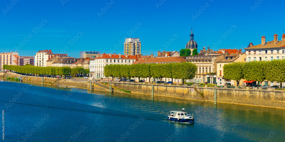 General view of Chalon-sur-Saone, French city in Saone-et-Loire department. Boat sailing through Saone River.
