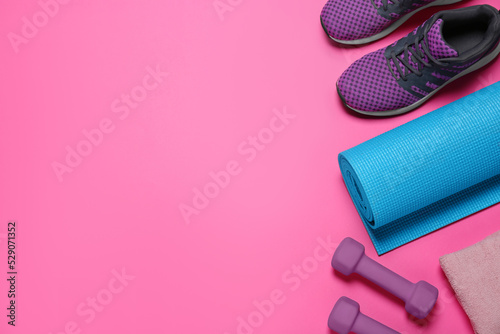 Exercise mat, dumbbells, towel and shoes on pink background, flat lay. Space for text
