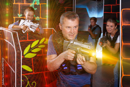 Portrait of fine man with laser gun having fun with family on laser tag arena © JackF