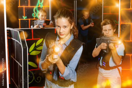 Portrait of cheerful teenager girl with laser gun having fun with her family on lasertag arena © JackF
