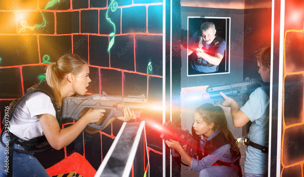 Smiling children with theirs parents holding laser guns and playing ...