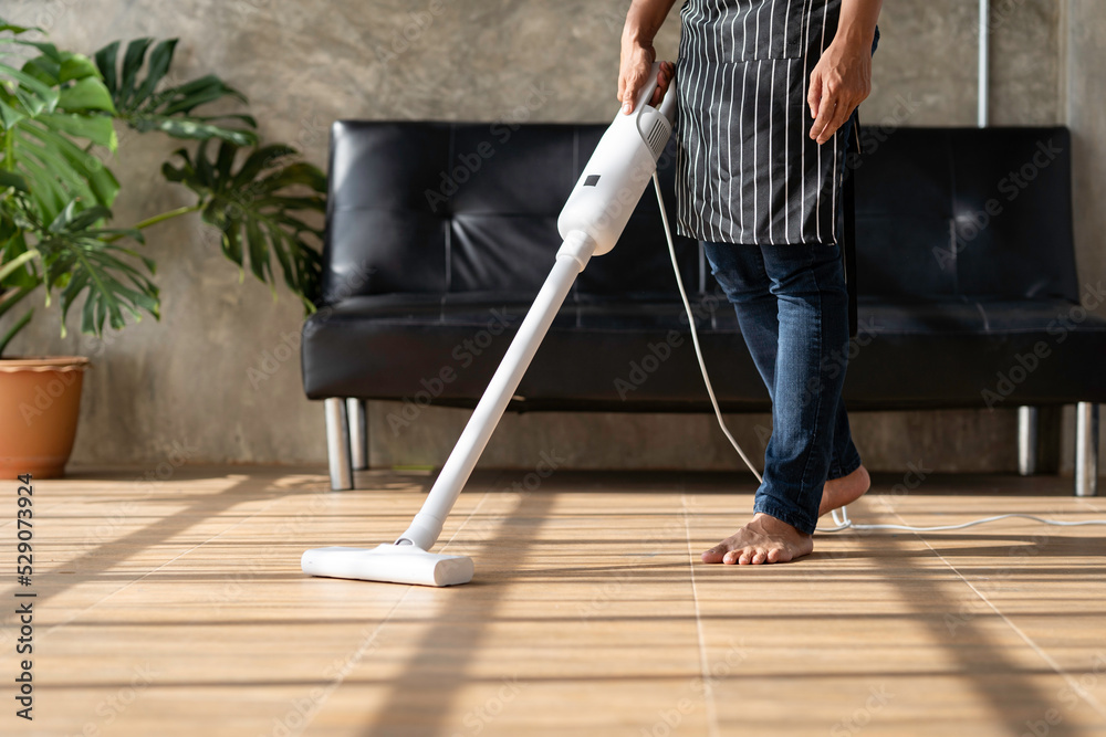 Fototapeta premium Vacuum Cleaner. A man does house work with a vacuum cleaner