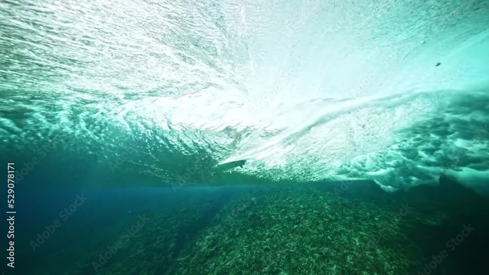 Underwater shot of male surfer silhouette riding barrel of a perfect