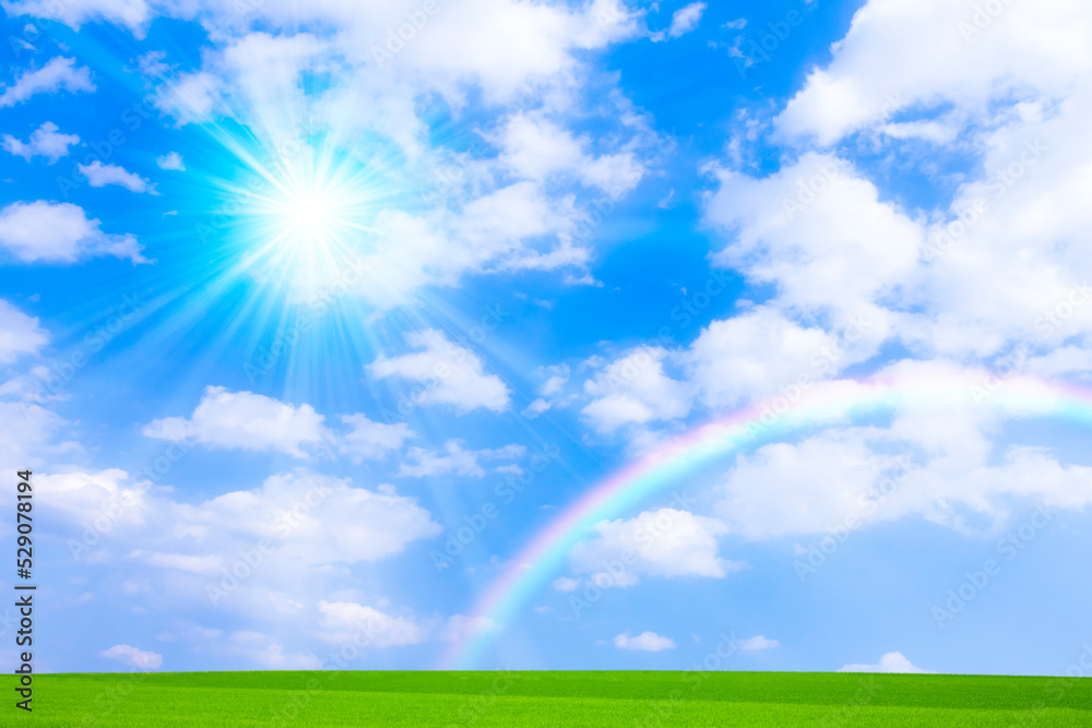 草原と青空に虹と太陽
