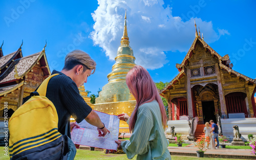 Young Asian travelers looking and studying site map of the beautiful Thai Buddhist temple, Wat Prasingh in Chiang Mai, Thailand. photo