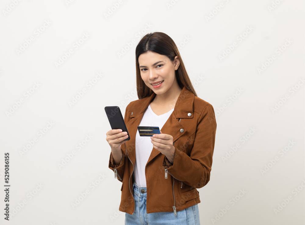 Excited Beautiful young woman using smartphone mobile and holding credit card standing on isolated white background. Shopping online input the serial number of credit card for payment Excited Beautiful young woman using smartphone mobile and holding credit card standing on isolated white background. Shopping online input the serial number of credit card for payment
