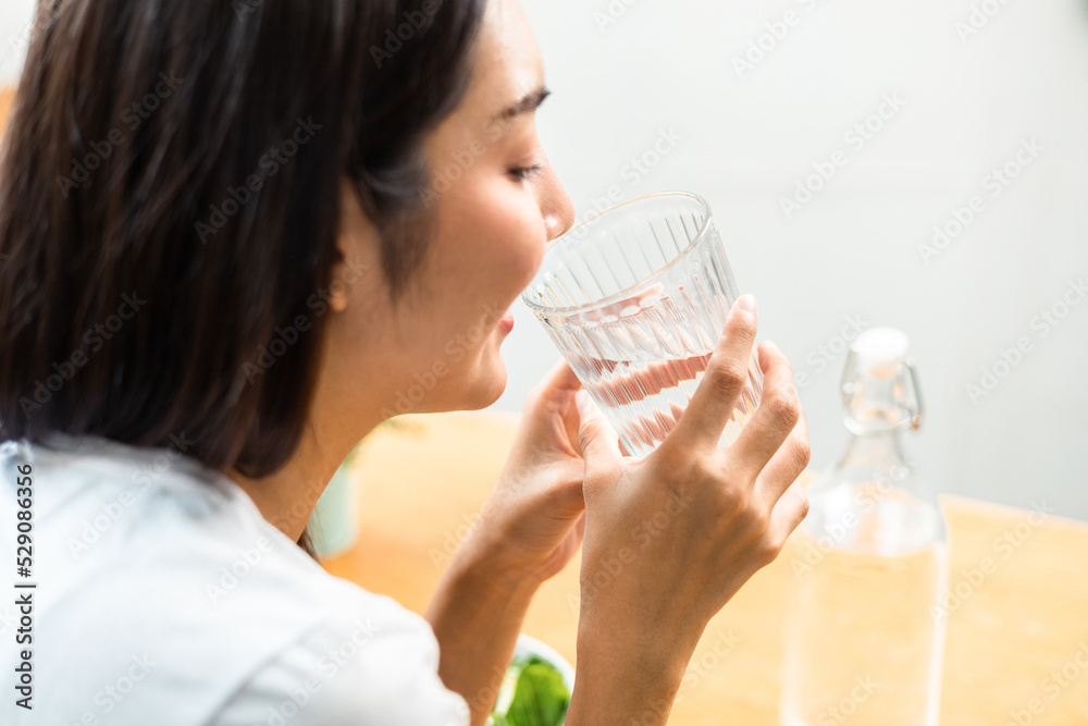Young female drinking water in glass for refreshing for diet and wellness on table. Beautiful woman happily drink fresh water before breakfast in kitchen in the morning. Healthy food concept. Young female drinking water in glass for refreshing for diet and wellness on table. Beautiful woman happily drink fresh water before breakfast in kitchen in the morning. Healthy food concept.