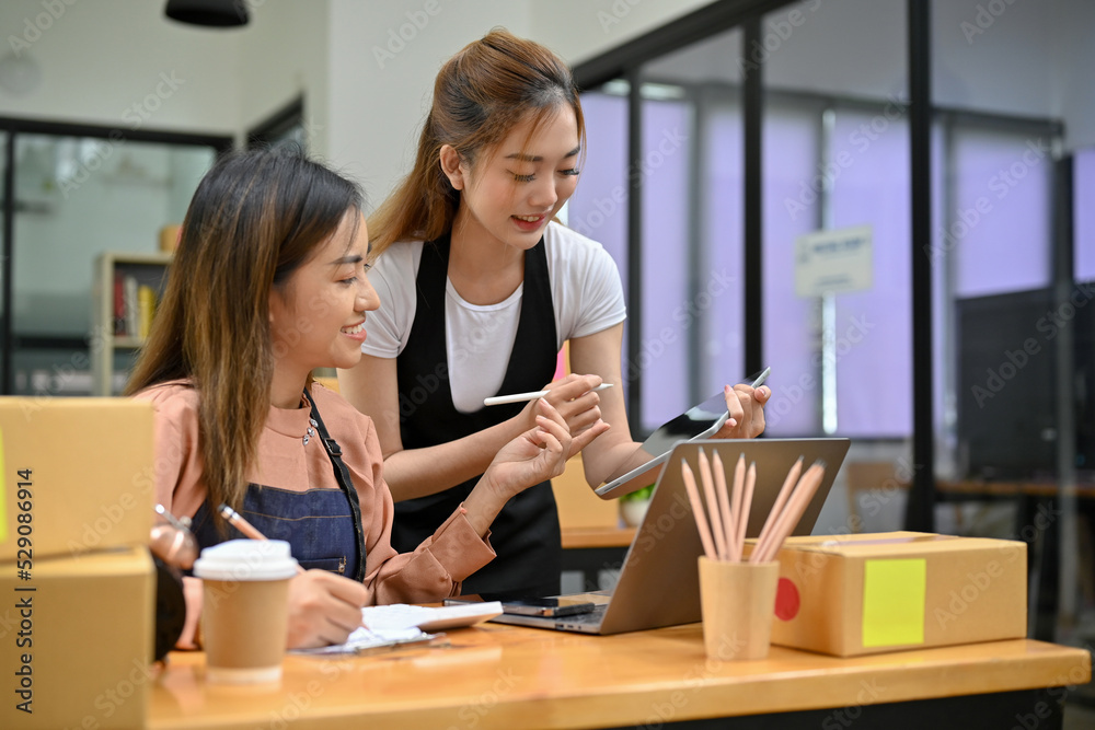 Two pretty Asian female small business owner working together in the stock office room Two pretty Asian female small business owner working together in the stock office room