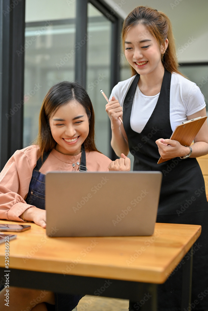 Two beautiful asian female small business entrepreneur checking their orders on laptop Two beautiful asian female small business entrepreneur checking their orders on laptop