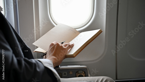 Successful Asian businessman reading a book during the flight for his business trip.